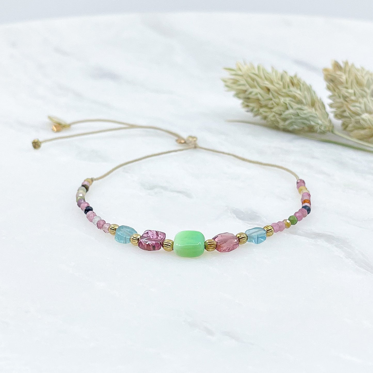 Bracelet ajustable en pierres fines naturelles. Au centre une Agathe d'Herbe carrée verte. Encadrée de deux Tourmalines et deux Aigue-marine.