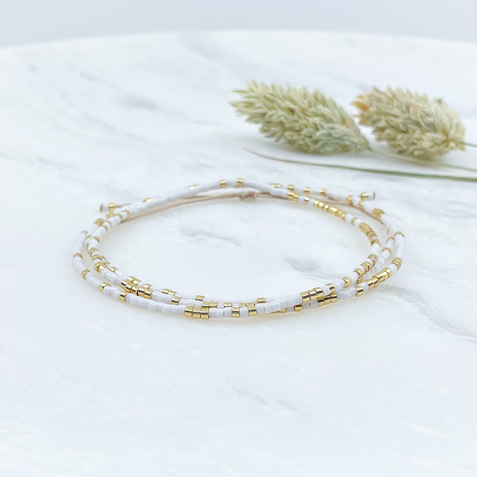 Bracelet ajustable en pierre de rocaille blanc et or. Trois tours de poignet