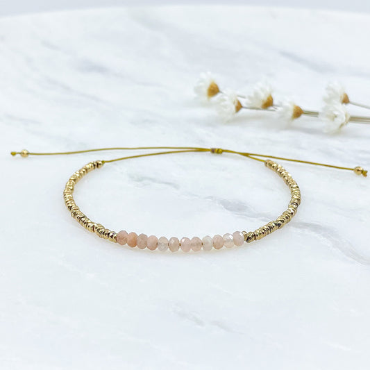 Bracelet ajustable en pierres fines naturelles Pierre de Soleil aux nuances rosées et perles d'hématites dorées.