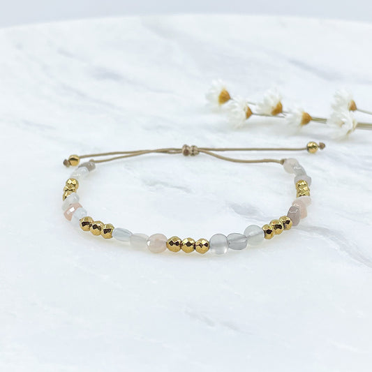Bracelet ajustable en pierres fines naturelles Pierre de Soleil aux nuances blanches et rosées et perles d'hématites dorées.