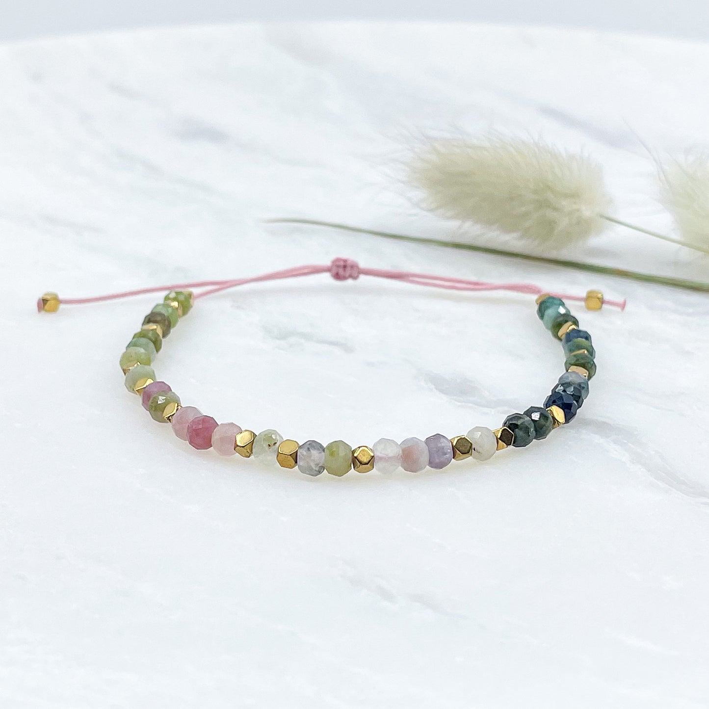 Bracelet ajustable composé de pierres fines naturelles de différentes teintes de Tourmaline ponctuées de perles d'hématites dorées.