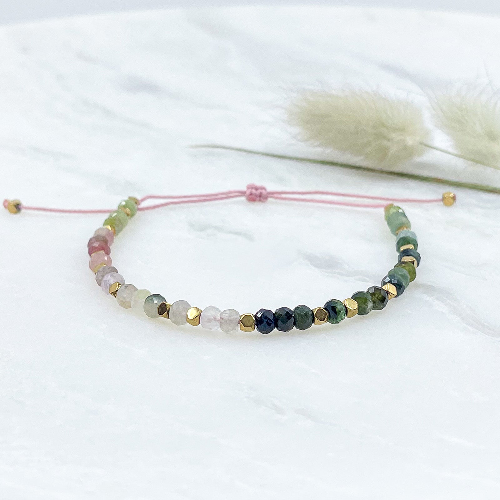 Bracelet ajustable composé de pierres fines naturelles de différentes teintes de Tourmaline ponctuées de perles d'hématites dorées.