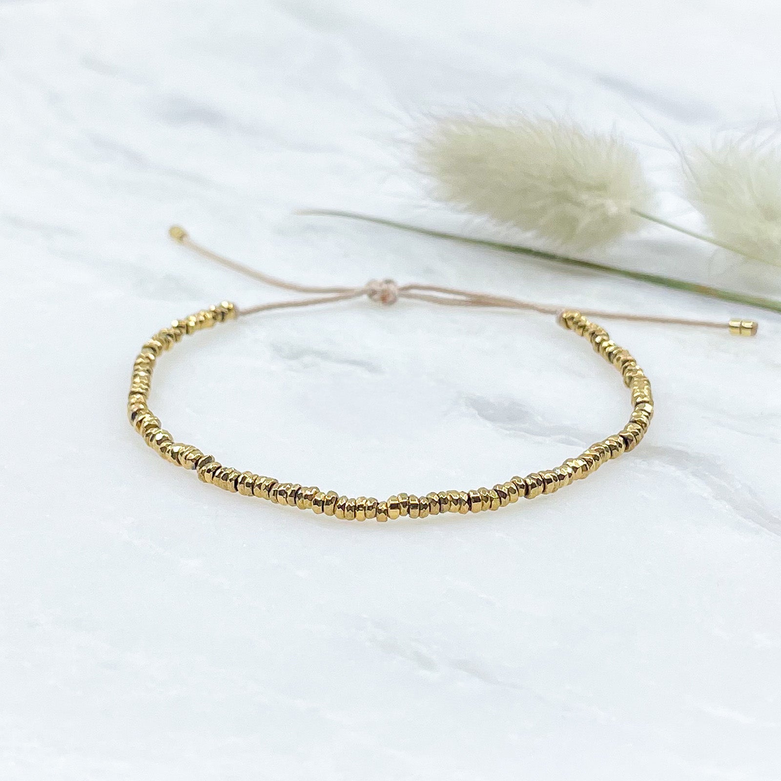 Bracelet en perles de pierre naturelle d'hématite dorée montées sur un cordon ajustable à la taille de votre poignet.