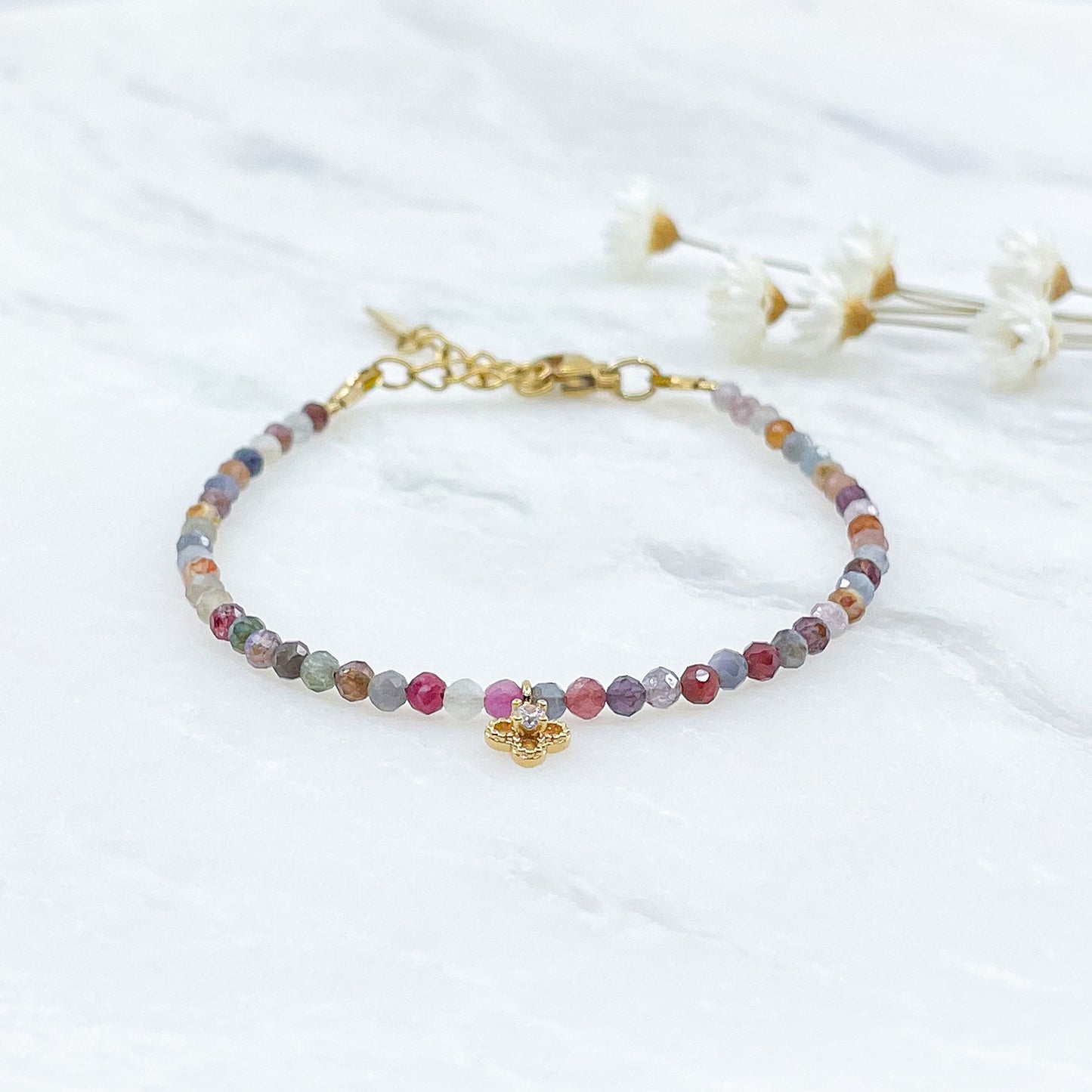 Bracelet pierres naturelles perles de tourmaline multicolores. En son centre un petit pendentif trèfle doré serti d'un cristal.