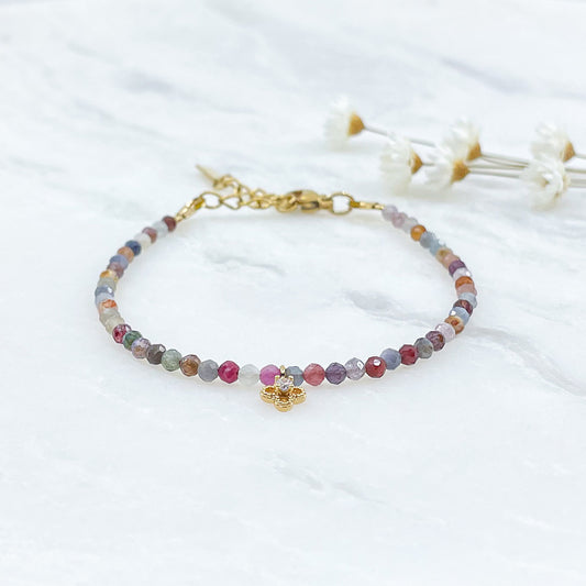Bracelet pierres naturelles perles de tourmaline multicolores. En son centre un petit pendentif trèfle doré serti d'un cristal.