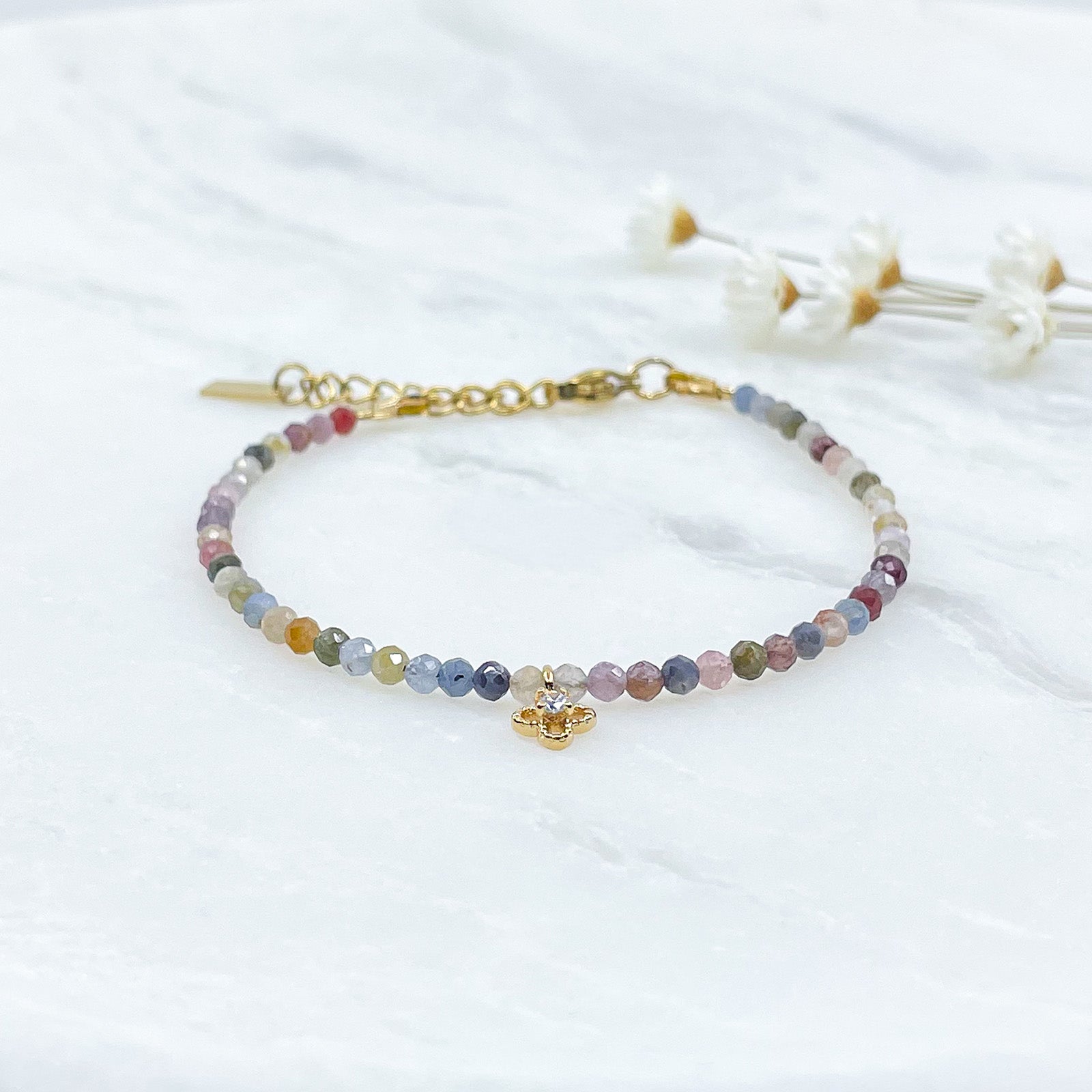 Bracelet pierres naturelles perles de tourmaline multicolores. En son centre un petit pendentif trèfle doré serti d'un cristal.