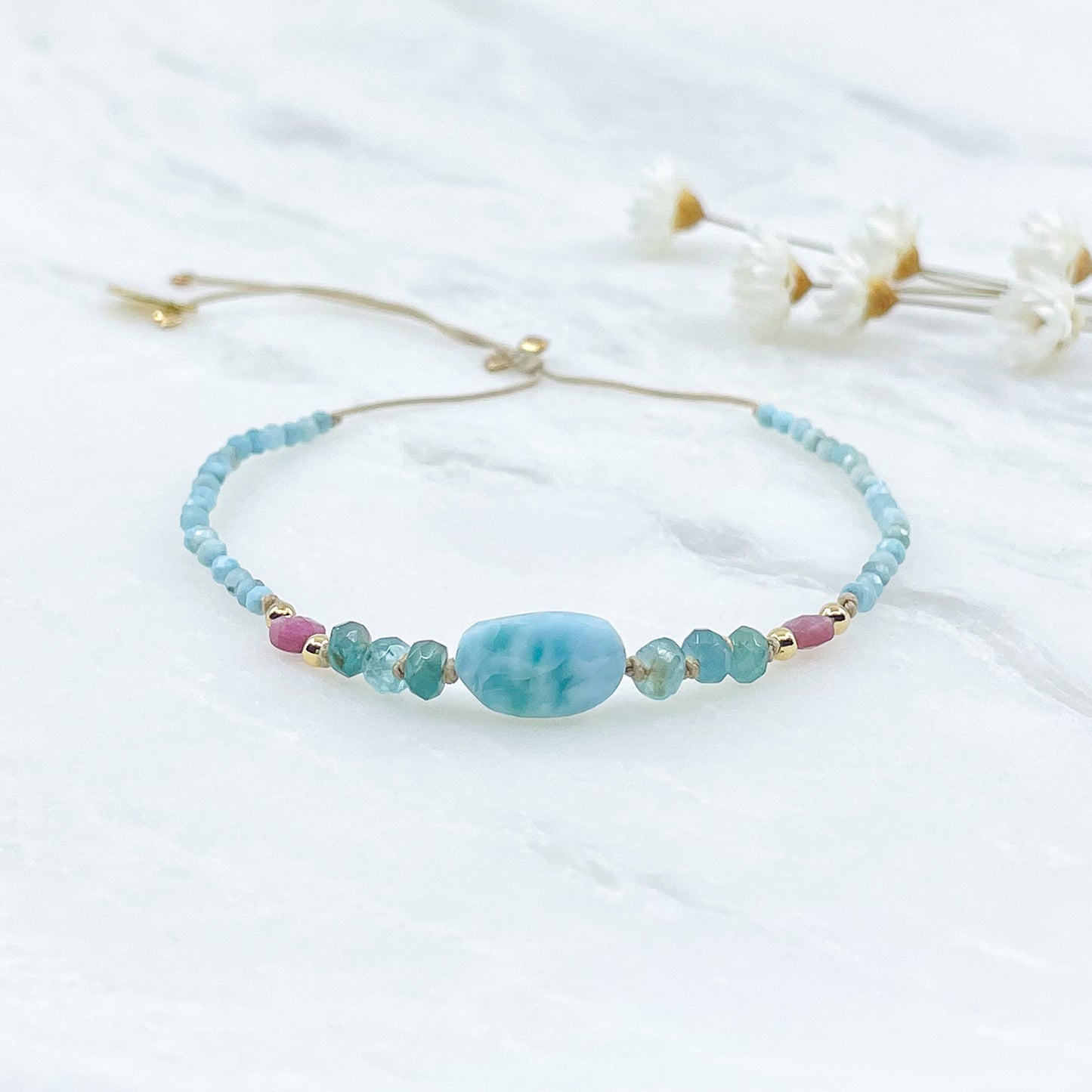 Bracelet aux teintes bleutées ajustable composé de pierres fines naturelles de larimar, d'une sélection de tourmaline et grandidierite encadrant un beau galet de Larimar bleu marin