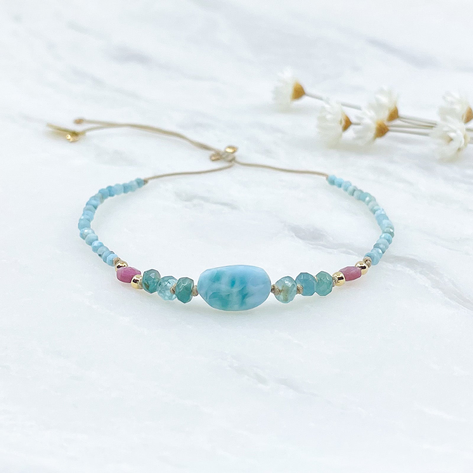 Bracelet aux teintes bleutées ajustable composé de pierres fines naturelles de larimar, d'une sélection de tourmaline et grandidierite encadrant un beau galet de Larimar bleu marin