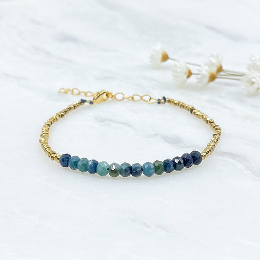 Bracelet en perles de pierres fines naturelles de Tourmaline bleu-vert intense. Elle sont encadrées de perles d'Hématites dorées.