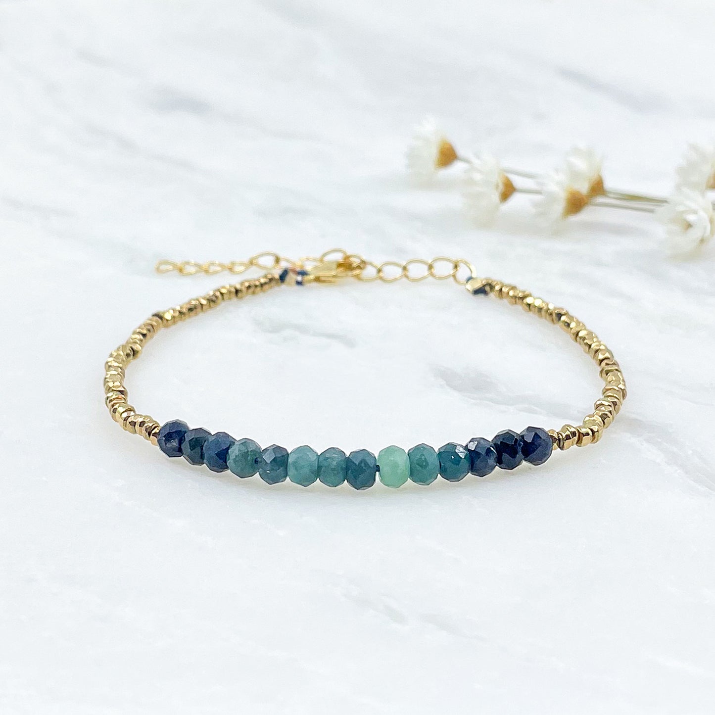 Bracelet en perles de pierres fines naturelles de Tourmaline bleu-vert intense. Elle sont encadrées de perles d'Hématites dorées.