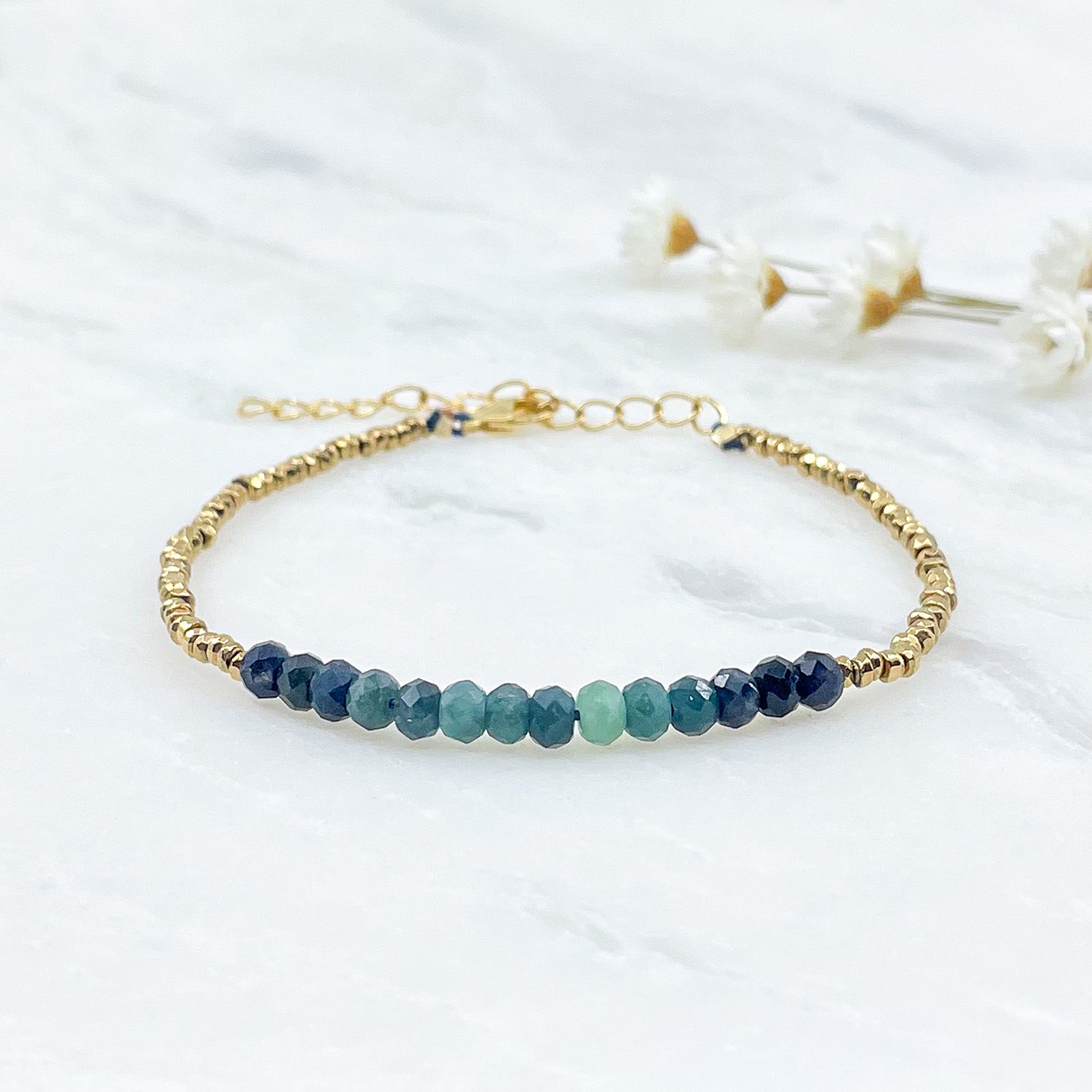 Bracelet en perles de pierres fines naturelles de Tourmaline bleu-vert intense. Elle sont encadrées de perles d'Hématites dorées.