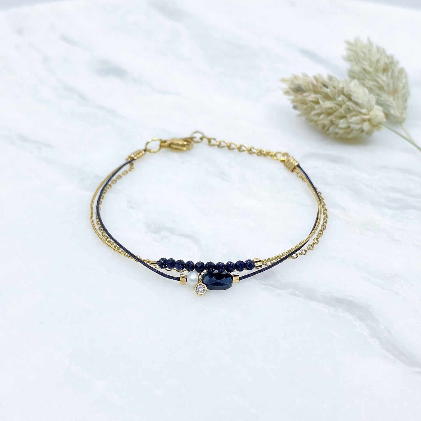 Bracelet Saphir Bleu Nuit - Perle de Culture montés sur différents liens cordons et chaîne dorée.