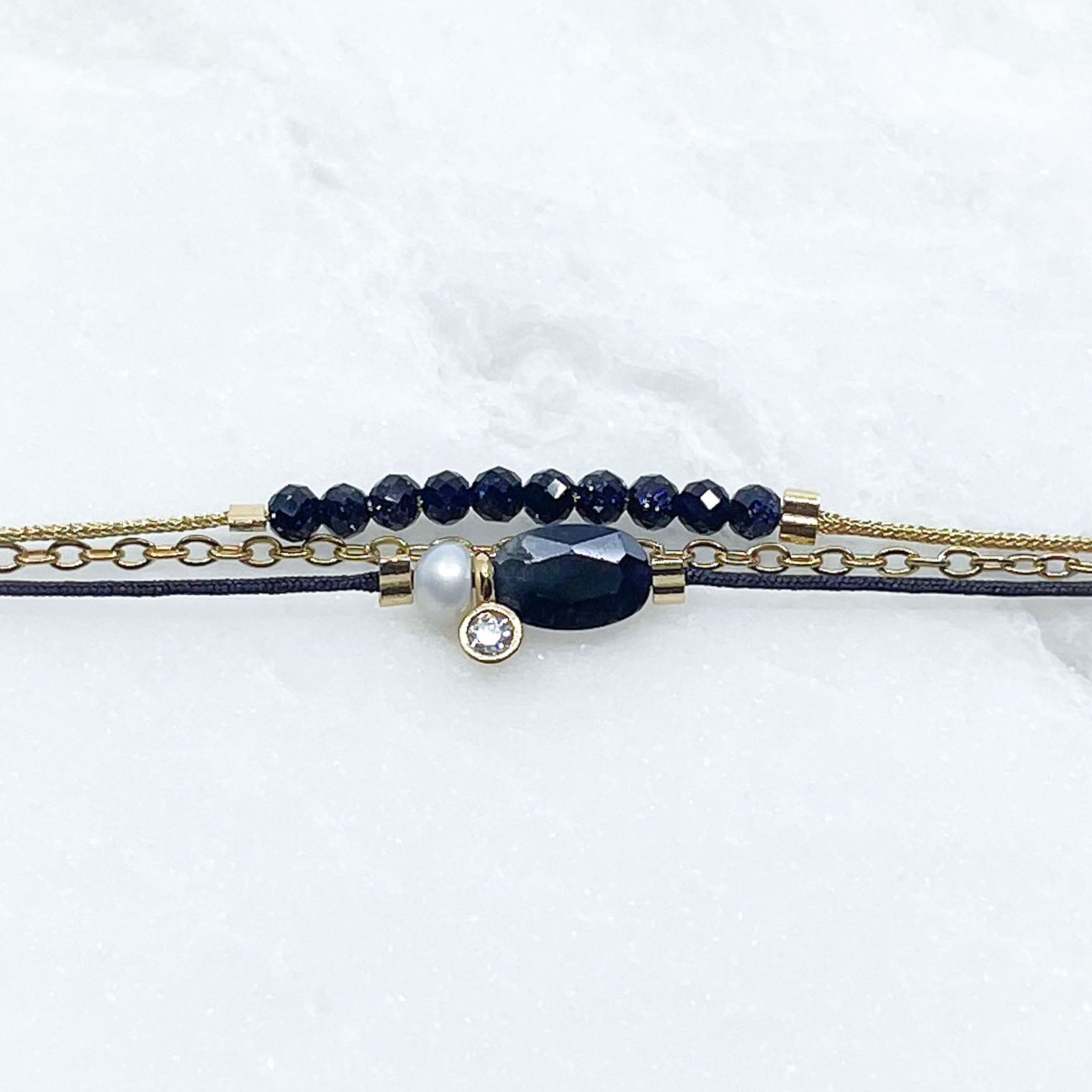Bracelet Saphir Bleu Nuit - Perle de Culture montés sur différents liens cordons et chaîne dorée.