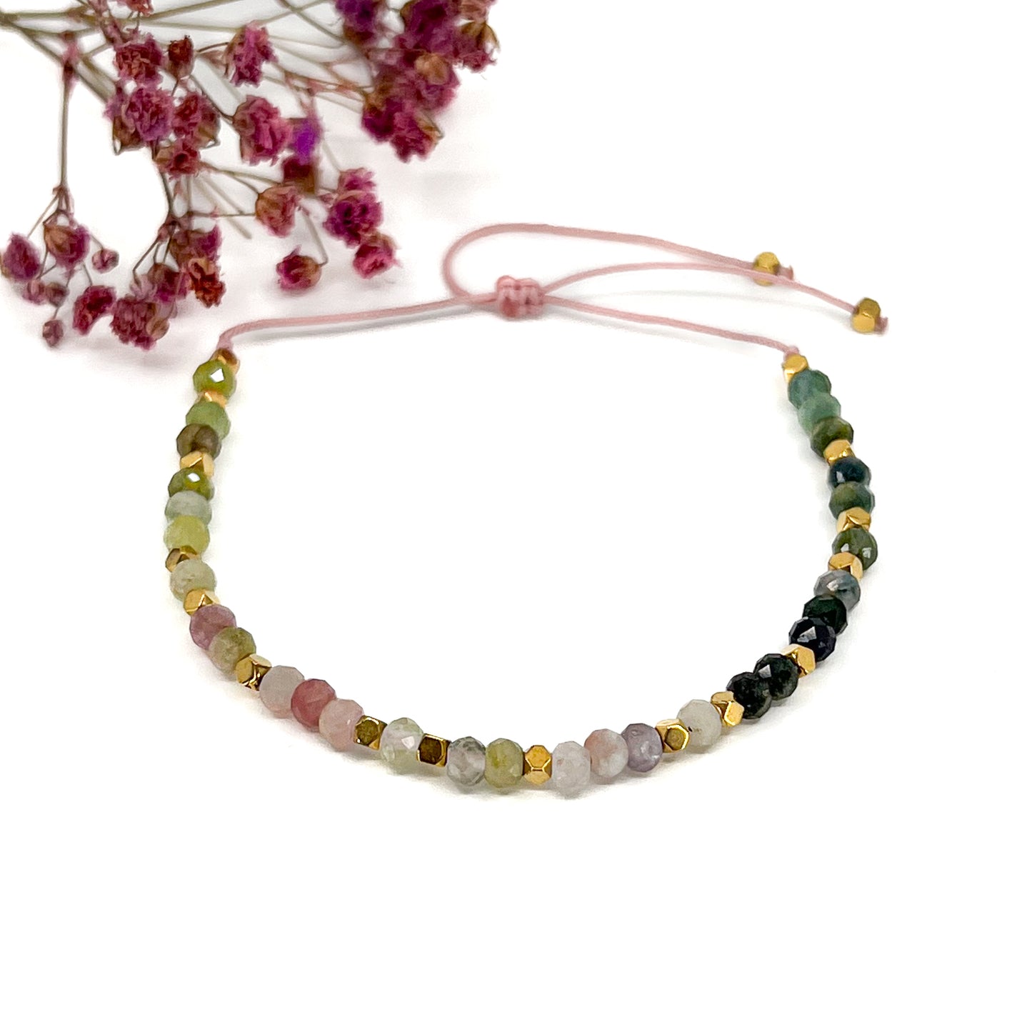 Bracelet ajustable composé de pierres fines naturelles de différentes teintes de Tourmaline ponctuées de perles d'hématites dorées.