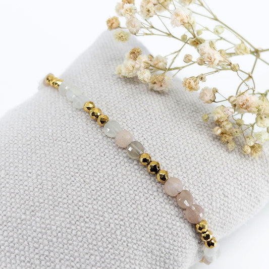 Bracelet ajustable en pierres fines naturelles Pierre de Soleil aux nuances blanches et rosées et perles d'hématites dorées.