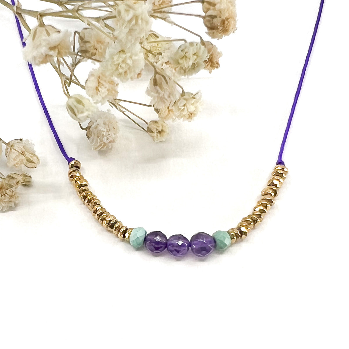 Collier sur cordon ajustable. Pierres fines naturelles : 3 perles d'améthyste encradrées par deux perles de Turquoise et des hématites dorées.