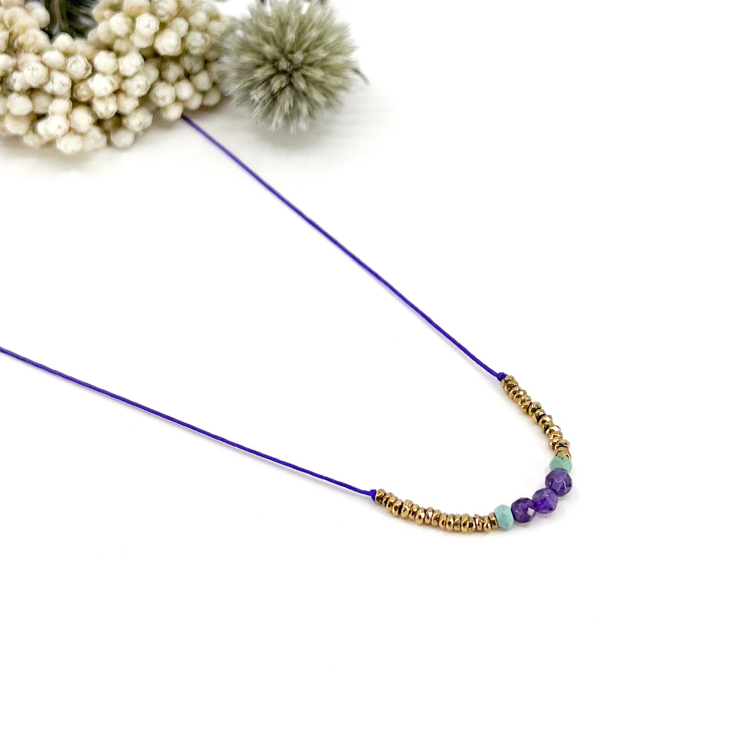Collier sur cordon ajustable. Pierres fines naturelles : 3 perles d'améthyste encradrées par deux perles de Turquoise et des hématites dorées.