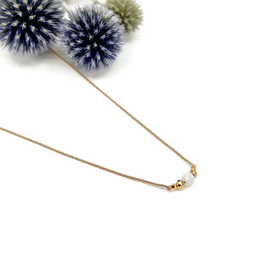 Collier cordon taille ajustable mettant en valeur une perle carrée facettée de pierre fine naturelle de Quartz Blanc entourée d'Hématite dorée.