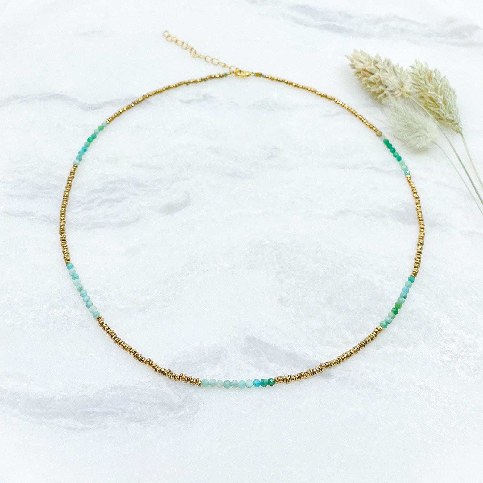 Collier en pierres fines naturelles d'amazonite aux différentes teintes de vert et hématite dorée. Longueur ajustable de 38-43 cm. Fermoir et chaîne d'extension en plaqué or.