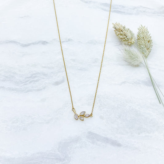 Collier plaqué or avec chaîne ajustable sur 3 niveaux de longueur différentes de 37 à 45 cm. Il met en valeur une brindille de feuillage réalisée en pierres fines naturelles de Pierre de Lune blanche au beaux reflets.