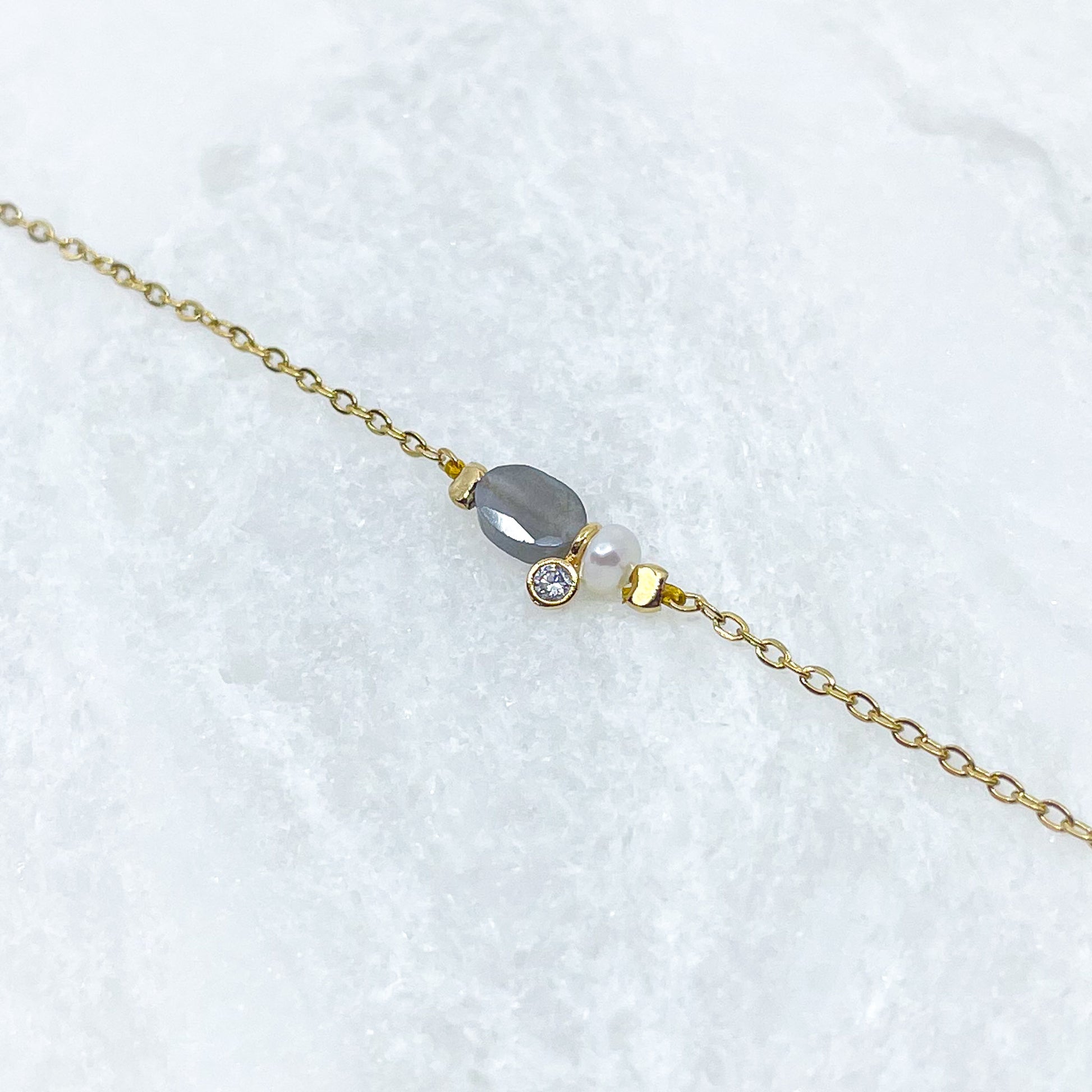 Collier en pierre fine naturelle Labradorite orné d'une perle de culture et d'un petit pendentif cristal éclatant. Monté sur chaîne dorée en acier inoxydable.