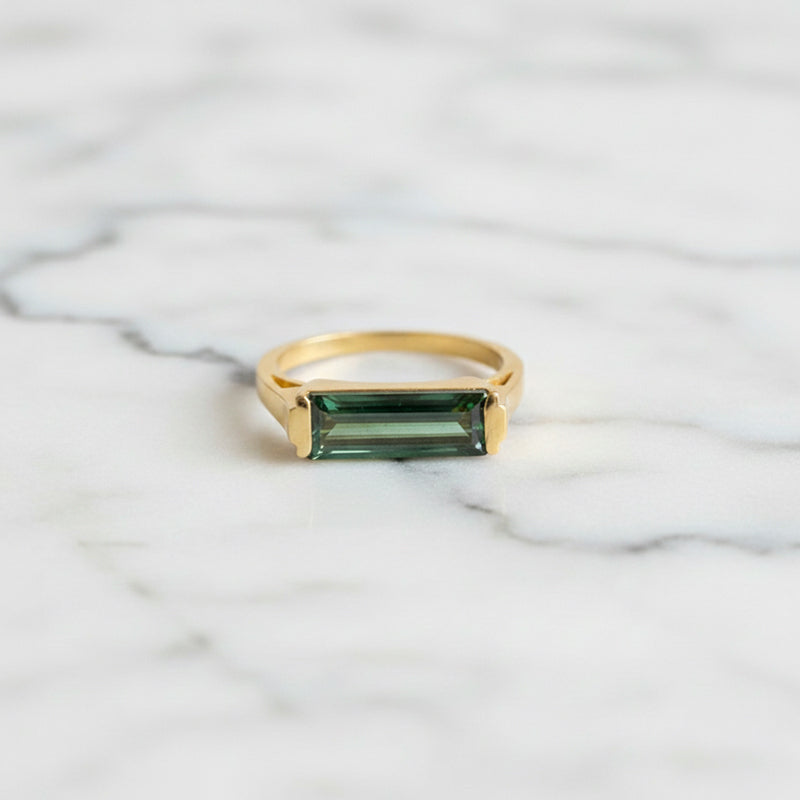Bague avec pierre de tourmaline verte rectangulaire montée sur un anneau en laiton plaqué or aspect mat.
