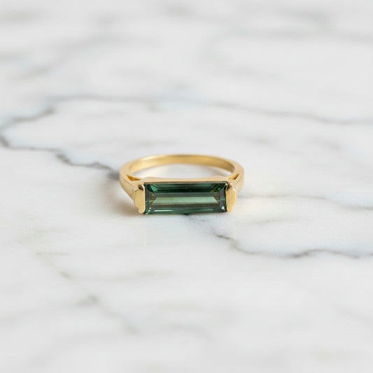 Bague avec pierre de tourmaline verte rectangulaire montée sur un anneau en laiton plaqué or aspect mat.