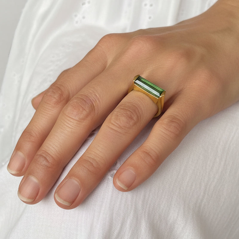 Bague avec pierre de tourmaline verte rectangulaire montée sur un anneau en laiton plaqué or aspect mat.