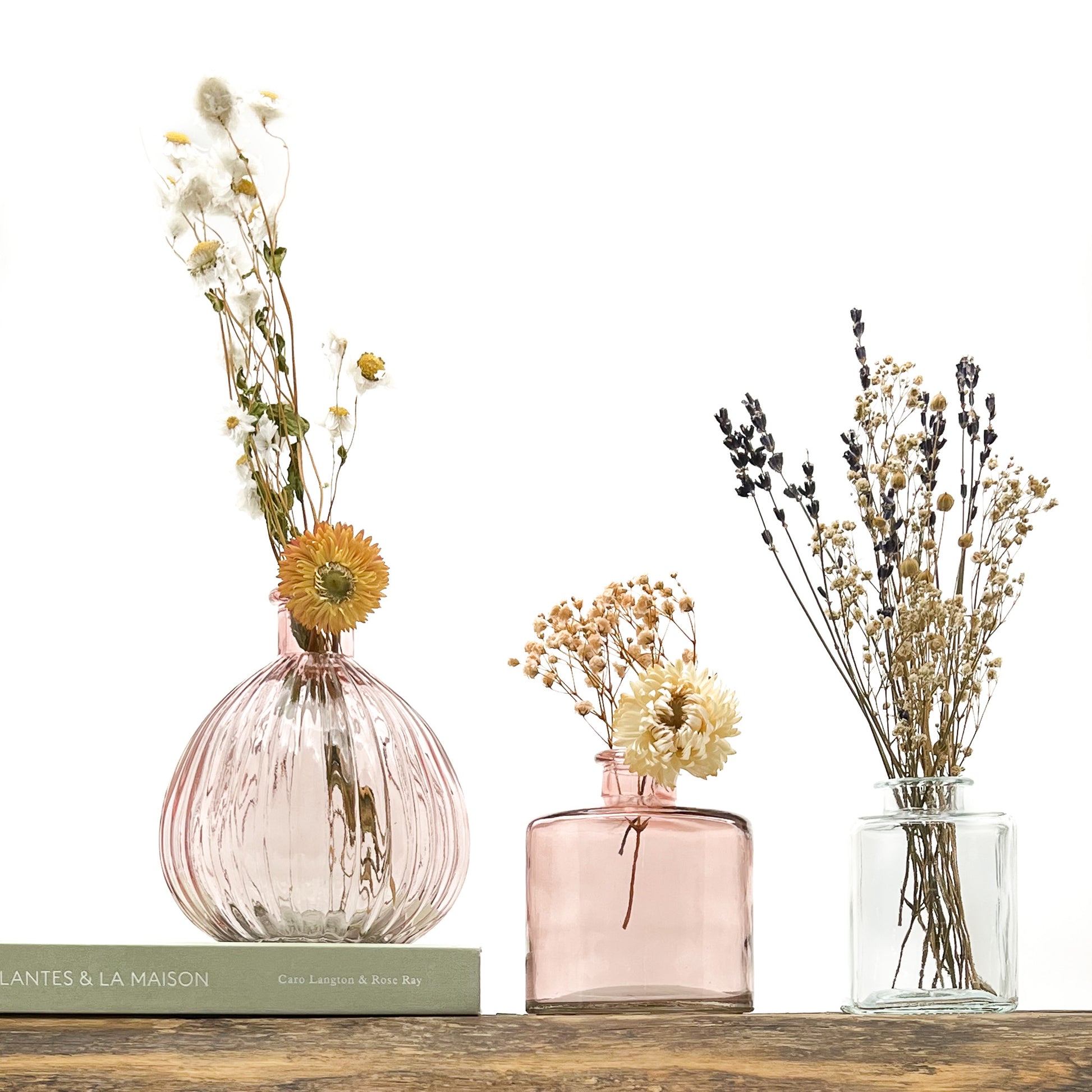Ensemble de 3 vases en verre, deux dans les tons rosé, le troisième translucide. Design différencié et harmonieux. Livrés avec fleurs séchées offertes.